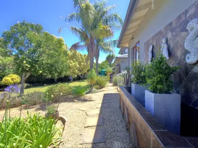 a house with a garden with trees and a sidewalk at Glennies Guesthouse in Somerset West