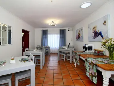 a dining room with tables and chairs and a table at Glennies Guesthouse in Somerset West