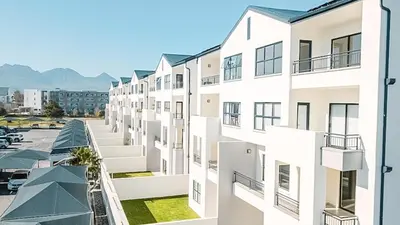 a row of white apartment buildings with a parking lot at Bright and airy Parisian Gem close to the beach in Cape Town