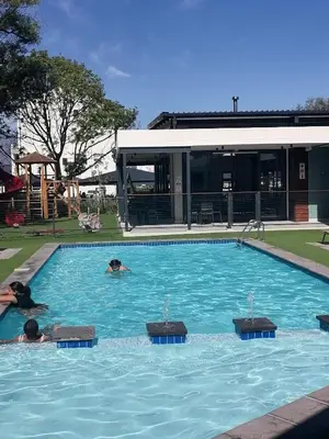 two people swimming in a large swimming pool at The Jade Somerset West in Cape Town