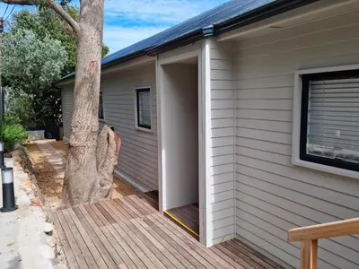 an open door on a deck next to a house at The Anchor, Luxury living for 2 with sea view and Jacuzzi in Gordonʼs Bay