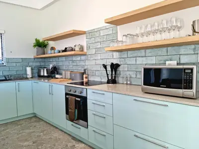 a kitchen with white cabinets and a microwave at The Anchor, Luxury living for 2 with sea view and Jacuzzi in Gordonʼs Bay