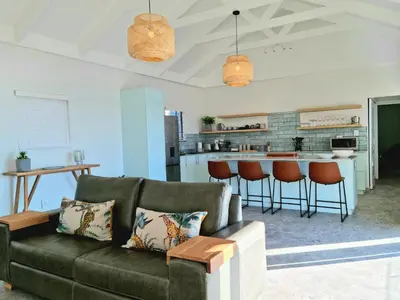 a living room with a couch and a kitchen at The Anchor, Luxury living for 2 with sea view and Jacuzzi in Gordonʼs Bay