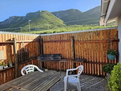 a patio with a wooden fence and a wooden table and chairs at Senelle accomodation in Hermanus