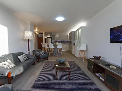 a living room with a couch and a table and a kitchen at Ocean-Song in Strand