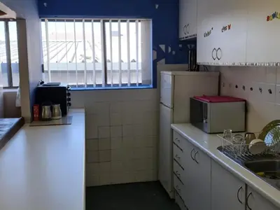 a kitchen with a sink and a refrigerator at Sunset beach backpackers in Bloubergstrand