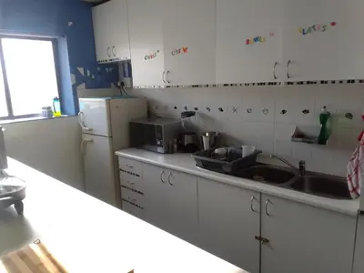 a kitchen with a sink and a refrigerator at Sunset beach backpackers in Bloubergstrand