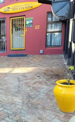 a yellow vase sitting in front of a building at Sunset beach backpackers in Bloubergstrand