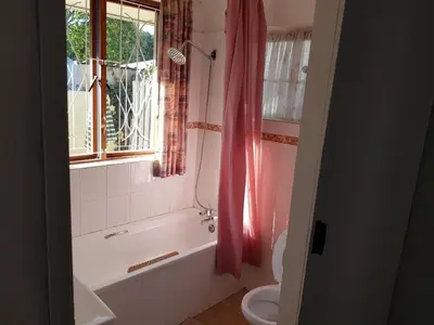 a bathroom with a tub and a toilet and a window at The Hermitage in Cape Town