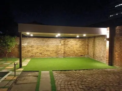 a building with a green lawn in front of a brick wall at Ojong's Court Bellville in Cape Town