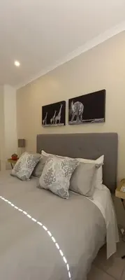 a bedroom with a bed with three pictures on the wall at Complete self-catering apartment close to the beach in Cape Town