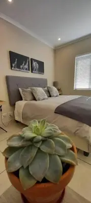 a bedroom with a large plant in front of a bed at Complete self-catering apartment close to the beach in Cape Town