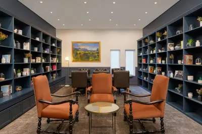 a waiting room with chairs and a table and bookshelves at Lord Charles Hotel, Somerset West, a Tribute Portfolio Hotel in Somerset West