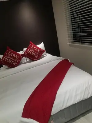 a bed with red and white pillows on it at Prince Olive in Cape Town