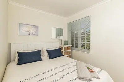 a bedroom with a bed with blue pillows and a window at Suburban bliss with Wifi and plunge pool in Cape Town