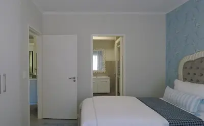 a bedroom with a white bed and a bathroom at Century City Mayfair Luxury Apartments in Cape Town