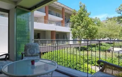 a balcony with a glass table and a building at Century City Mayfair Luxury Apartments in Cape Town