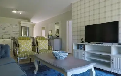 a living room with a tv and a table and chairs at Century City Mayfair Luxury Apartments in Cape Town