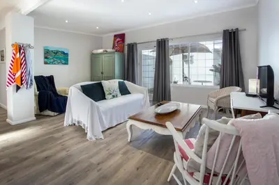 a living room with a couch and a table at Goozi Garden Cottage in Hermanus