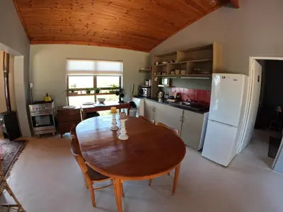 a kitchen with a wooden table and a refrigerator at Edible Shores in Pringle Bay