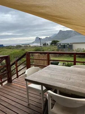 a wooden deck with a wooden table and chairs at Edible Shores in Pringle Bay