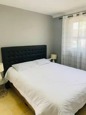 a bedroom with a large white bed with a black headboard at SpaciousNetflix#Wifi#Parking#CentralWinefarms#Mall in Cape Town