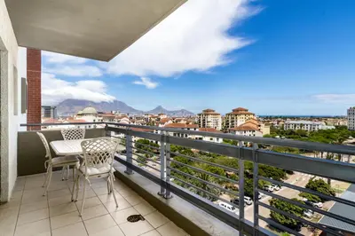 a balcony with chairs and a view of a city at The Manhattan Apartments in Cape Town