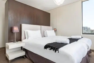 a bedroom with a large white bed with a wooden wall at The Manhattan Apartments in Cape Town