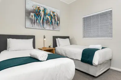 a bedroom with two beds and a painting on the wall at The Axis Luxury Apartments in Cape Town
