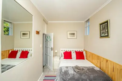 a bedroom with two beds and red pillows at Villa Garda B&B in Cape Town