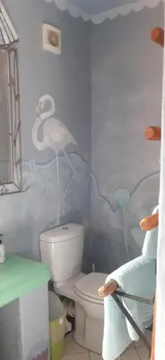 a bathroom with a toilet with a bird painted on the wall at Gecko Cottage at Artemis in Franschhoek