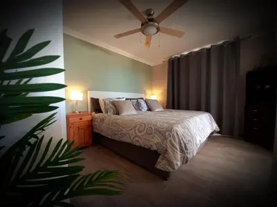 a bedroom with a bed and a ceiling fan at Bay-Side Apartment, Gordon's Bay in Gordonʼs Bay