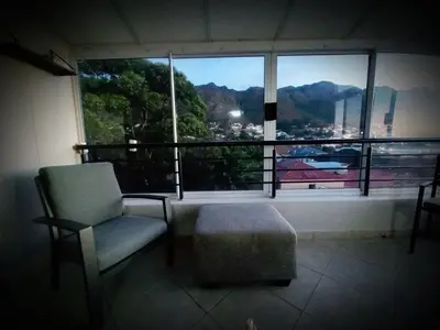 a room with a chair and a window with a view at Bay-Side Apartment, Gordon's Bay in Gordonʼs Bay