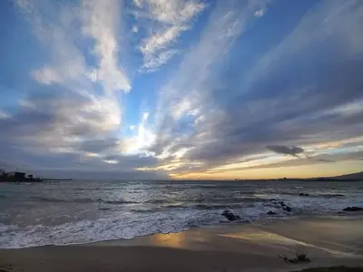 a sunset on the beach with the ocean at Bay-Side Apartment, Gordon's Bay in Gordonʼs Bay