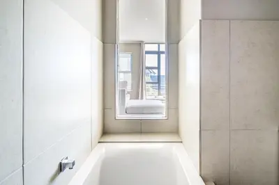 a bathroom with a tub and a chair in a window at Belina - Quayside Canal Front in Cape Town