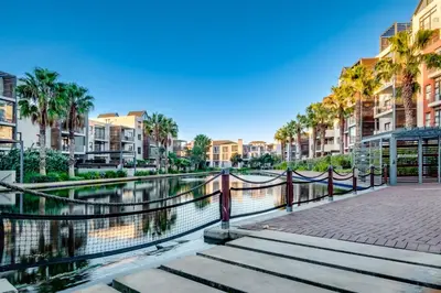 a river with palm trees and buildings next to a canal at Belina - Quayside Canal Front in Cape Town