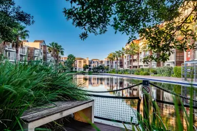 a bench in front of a pond with buildings at Belina - Quayside Canal Front in Cape Town