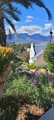 a church with flowers in the foreground and mountains in the background at De Molen Guest House in Somerset West