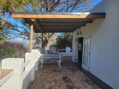 a patio with a wooden pergola and a bench at De Molen Guest House in Somerset West