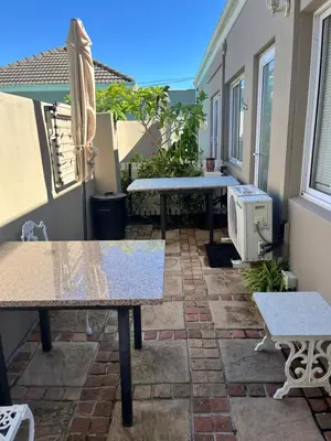 a patio with two tables and an umbrella at Somerset West All Stay 1 in Somerset West