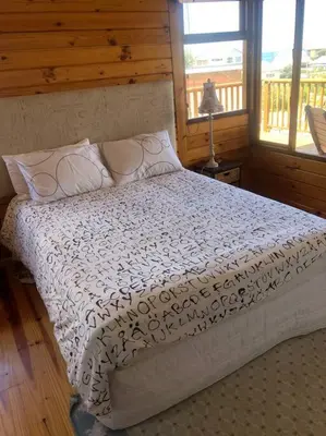 a bedroom with a bed with a white comforter at Adorable 2 bedroom seaside vacation home in Kleinmond