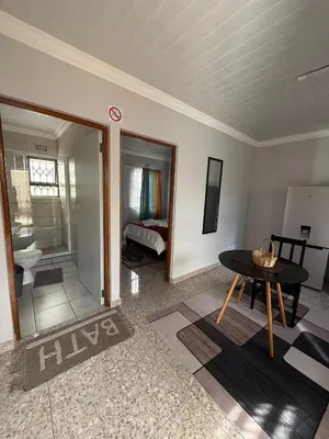 a living room with a table and a bedroom at Finca Guest House in Cape Town