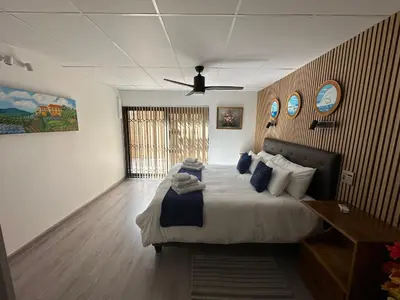 a bedroom with a large bed with a ceiling fan at Strelitzia, spacious with a stunning view in Cape Town