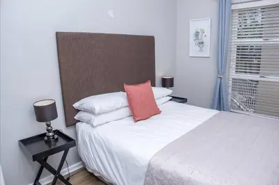 a bedroom with a bed with a red pillow on it at A Touch of Country in Stellenbosch
