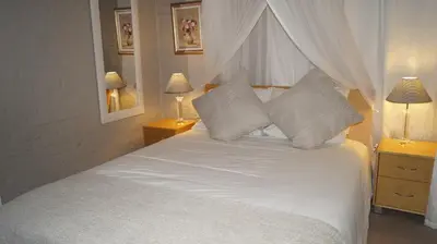 a bedroom with a white bed with pillows and two lamps at Valentines Hermanus in Hermanus