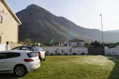 two cars parked in a yard with a mountain in the background at Valentines Hermanus in Hermanus