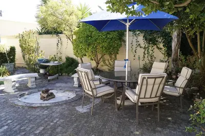 a patio with a table and chairs and an umbrella at Valentines Hermanus in Hermanus