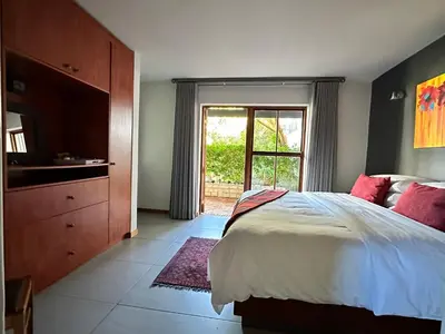 a bedroom with a bed and a dresser and a window at Hidden Gem on Onrus River in Hermanus