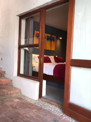 a bedroom with a bed through a glass door at Hidden Gem on Onrus River in Hermanus