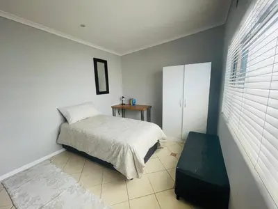 a bedroom with a bed and a white cabinet at Sixth Avenue Residence Halaal Accommodation Cape Town in Cape Town